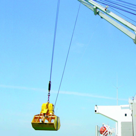 Electro-hydraulic clamshell grab type EHS-B hanging from a ship's crane, a worker supervises the work under an almost cloudless sky