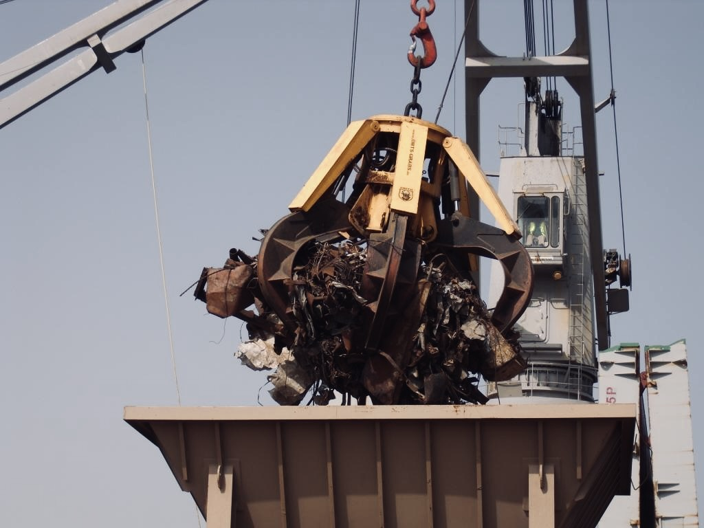 Elektro- hydraulischer Mehrschalengreifer entlädt Schrott am Hafen