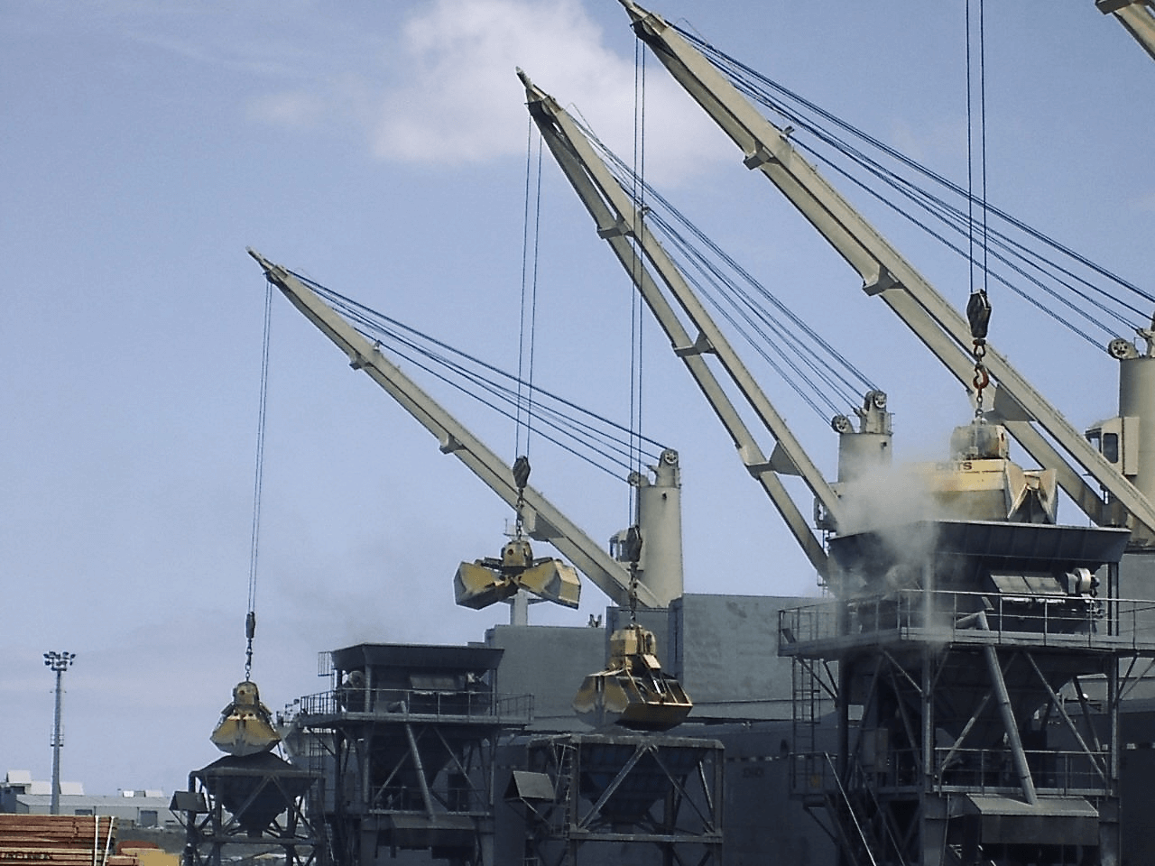 Drei diesel-hydraulische Zweischalengreifer laden am Hafen Material um